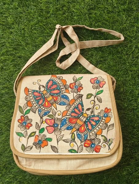 Butterfly motif Madhubani jute bag laid flat on grass